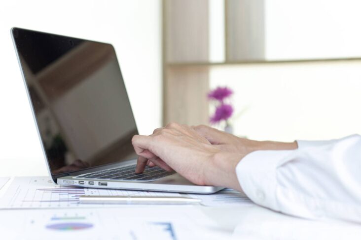 Mãos de uma mulher a escrever num computador portátil, enquanto está a preencher um ato único