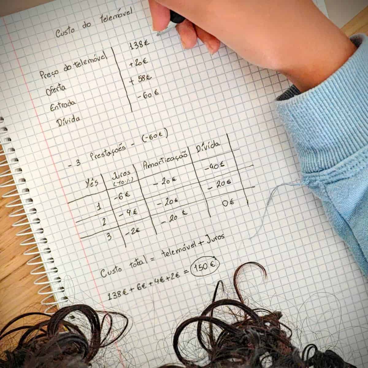 Criança aponta as condições de pagamento de um telemóvel com recurso a crédito. Numa folha de papel identifica o valor do equipamento, quanto tem de poupanças e qual será o montante de crédito necessário