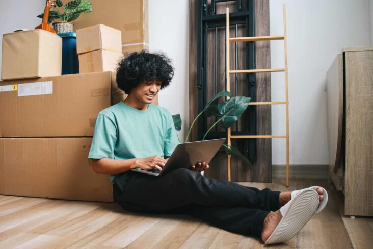 jovem ao computador na sua nova casa