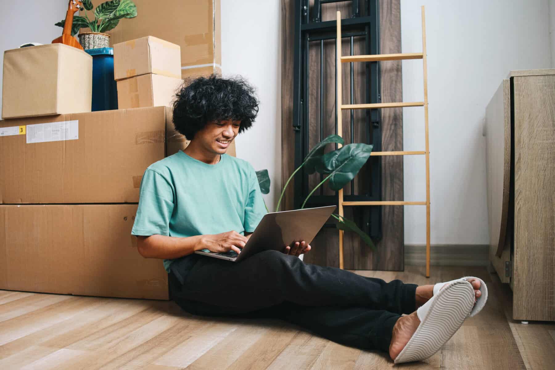 jovem ao computador na sua nova casa