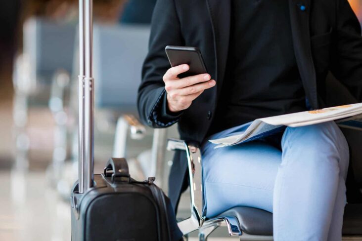 pessoa no aeroporto a com o telemóvel na mão a garantir que todos os dados estão corretos na app registo do viajante