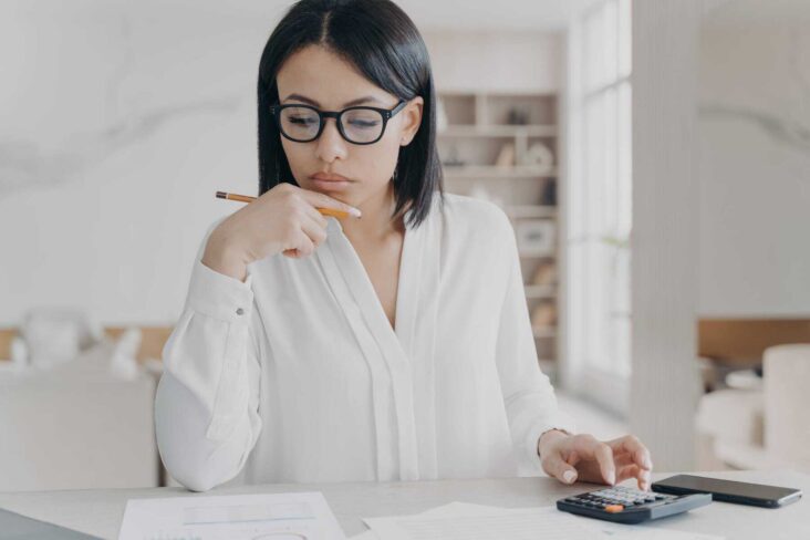 mulher a analisar as suas contas todas com uma calculadora durante um check up às suas finanças pessoais