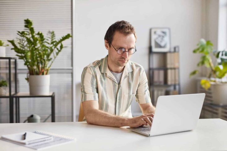 Homem está sentado numa secretária ao computador a analisar um pedido de crédito pessoal