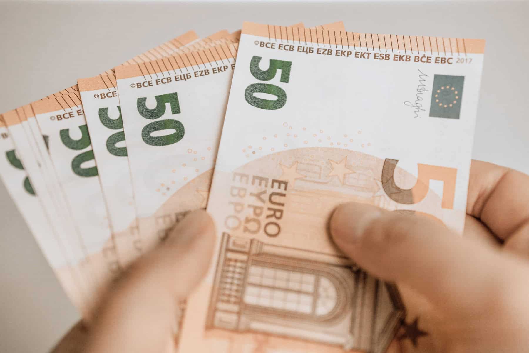 Mão de homem segura várias notas de 50 euros, numa alusão a crédito