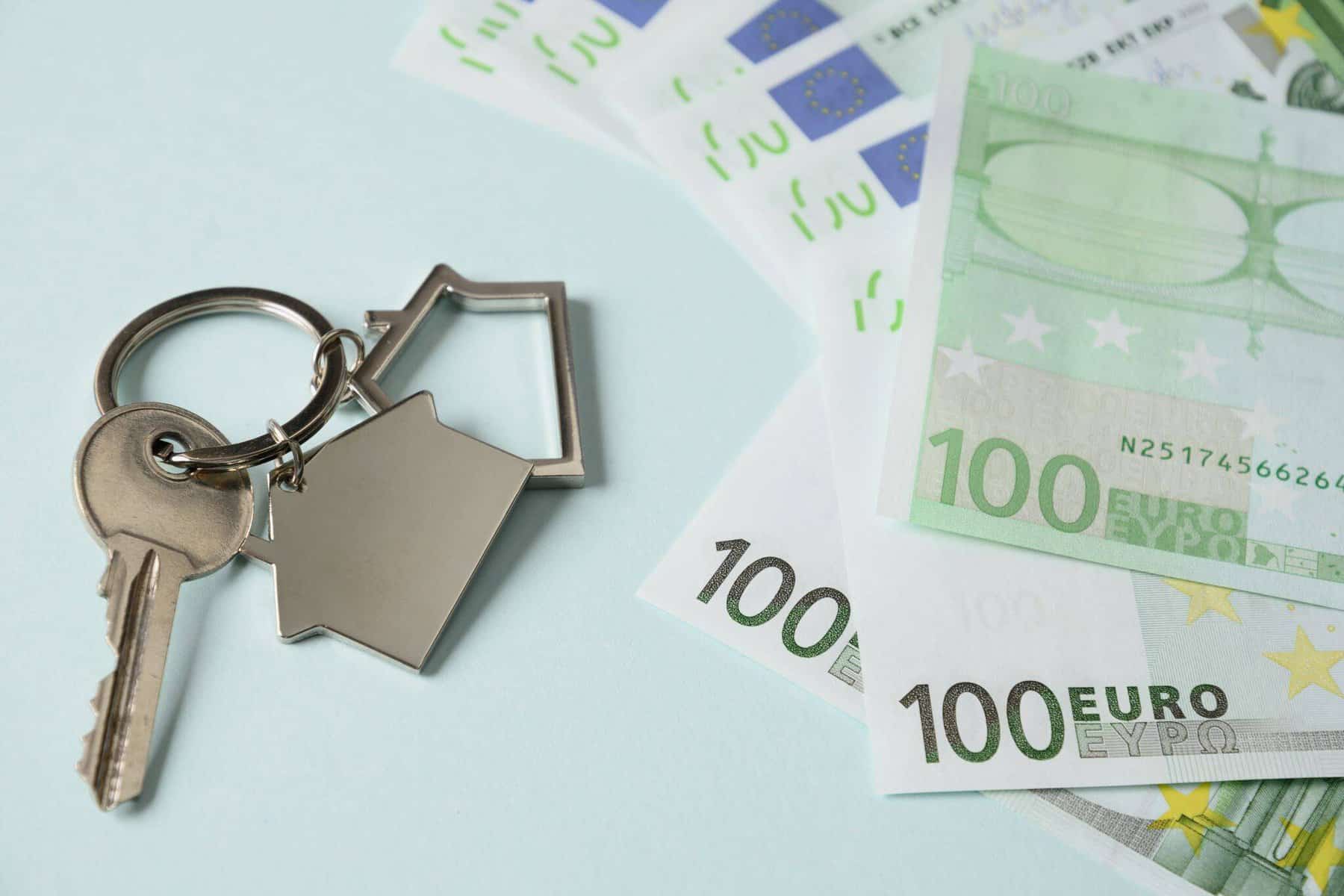 chave de casa e notas de 100 euros a ilustrar o pagamento do imposto do selo na compra de imóvel