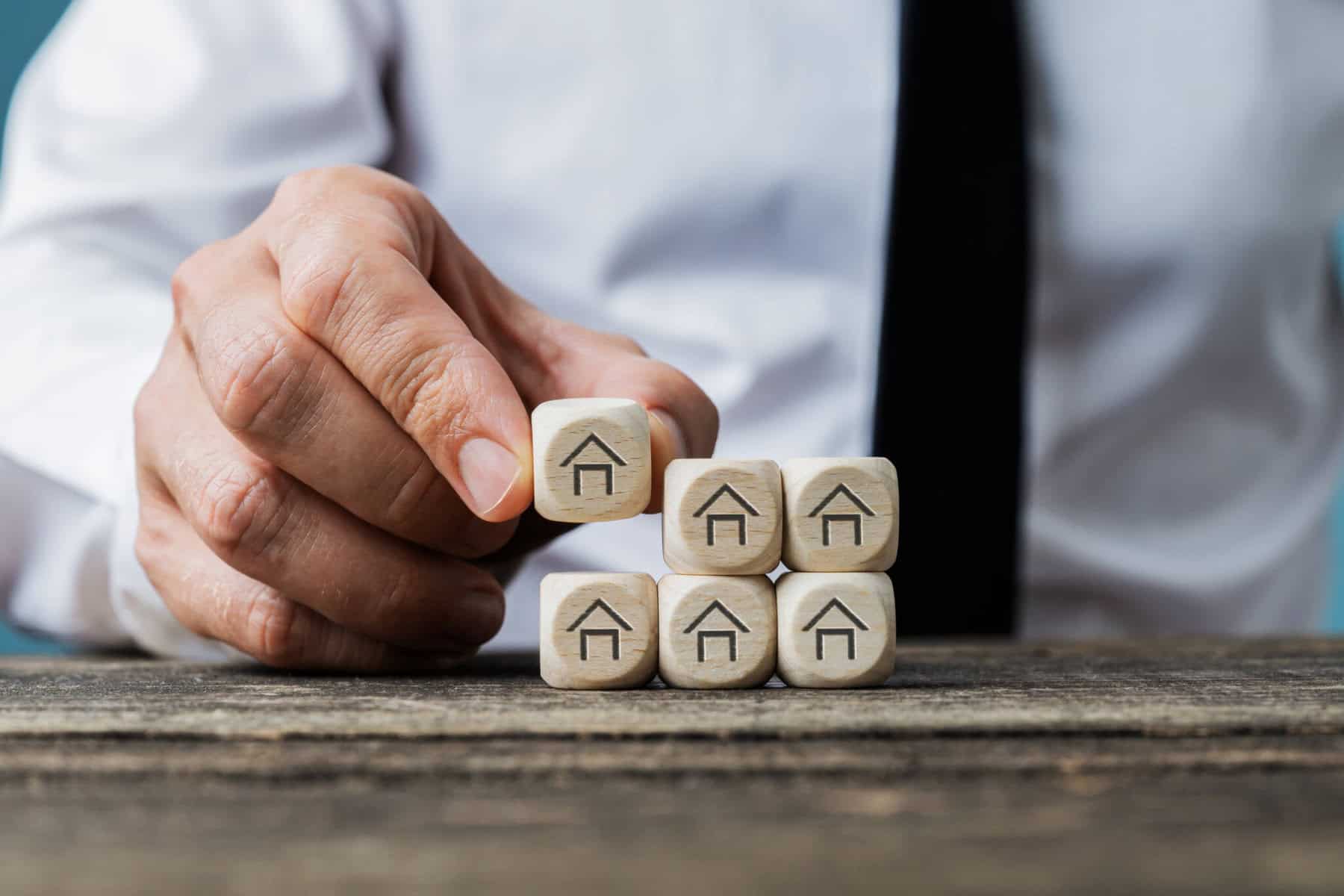 homem a empilhar dados com desenho de casas