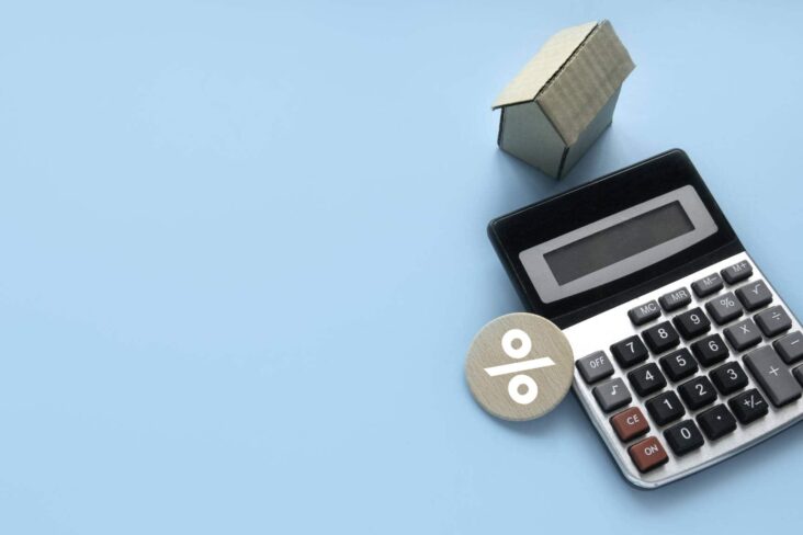 calculadora com maquete de casa e símbolo de percentagem