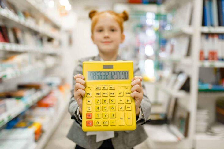 Menina no corredor do material escolar, com uma calculadora na mão a mostrar um valor elevado.
