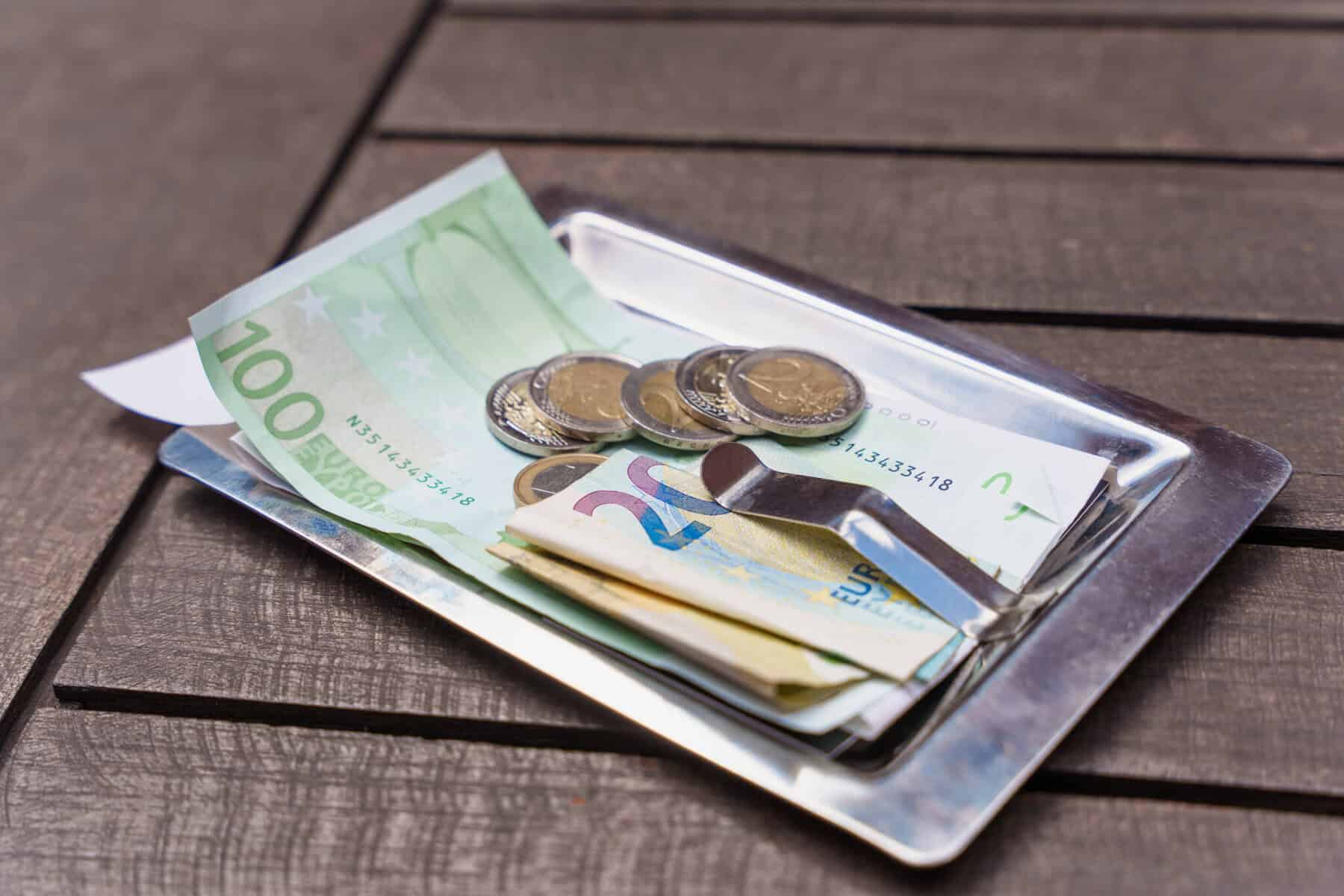 Nota e moedas deixadas num restaurante pelo cliente a ilustrar como são tributadas as gorjetas