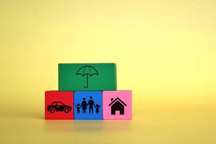 Três cubos coloridos com desenhos de um carro, uma família e uma casa. Por cima, está uma quarto cubo com um chapéu de chuva desenhado, numa alusão aos seguros de vida