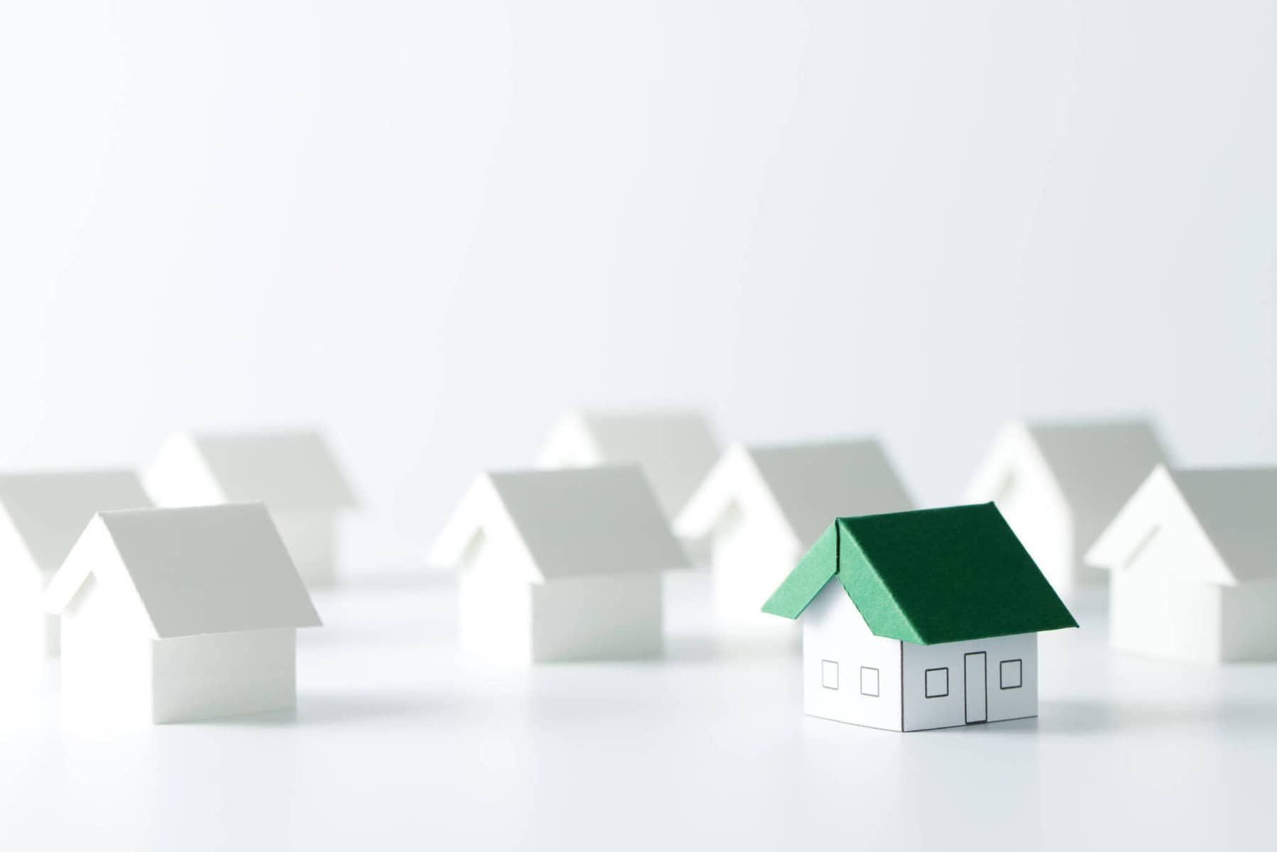 Pequenas casas brancas dispostas, a lembrar um bairro. Uma das casas em miniatura tem um telhado verde