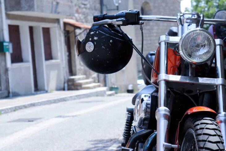 Moto estacionada do lado direito da rua. O capacete está pendurado no guiador, numa alusão a um seguro de vida