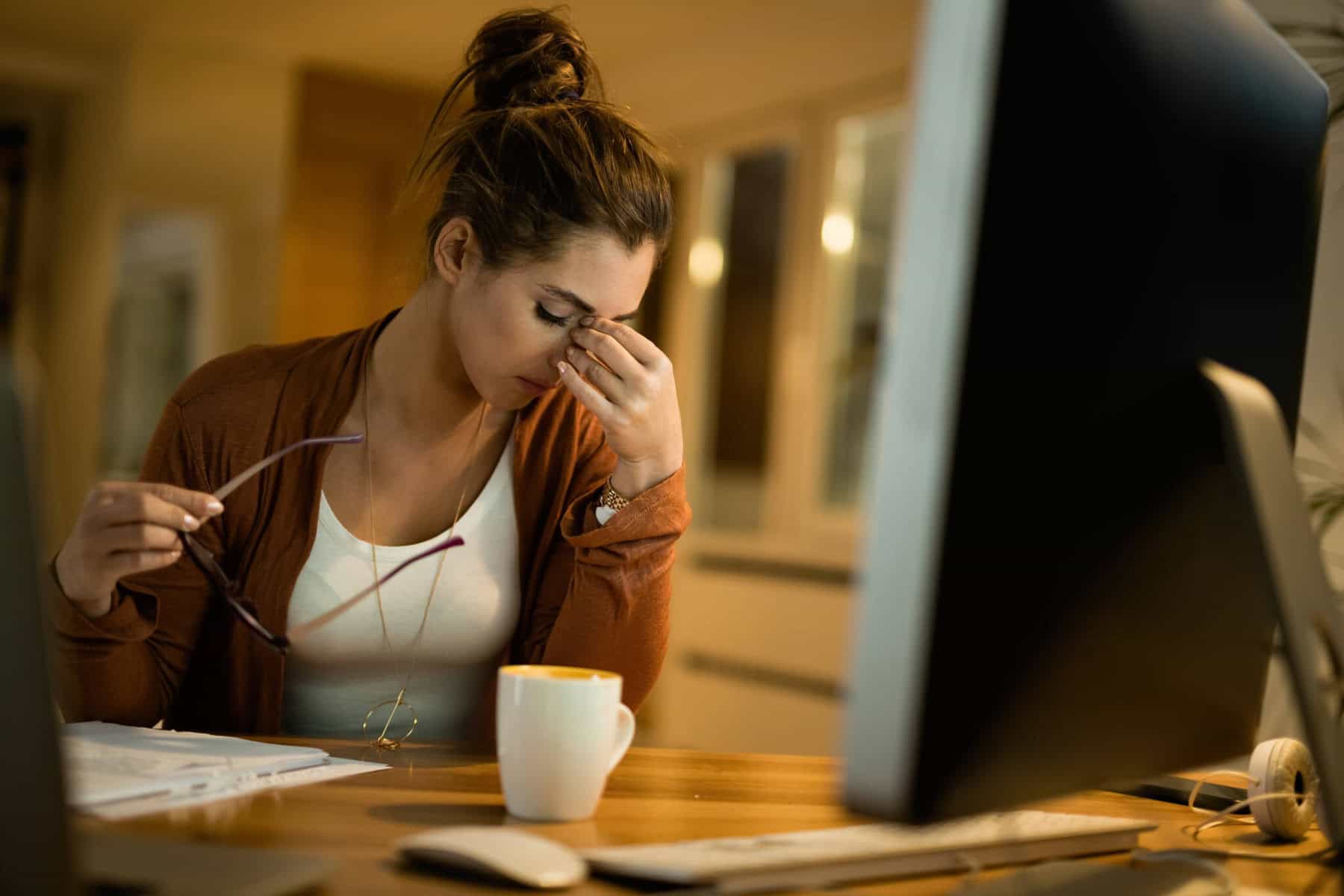 Jovem trabalhadora, sentada ao computador, demonstra cansaço, num período em que está a trabalhar em regime de trabalho noturno,