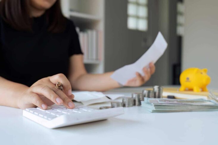 mulher com calculadora e papéis para analisar a poupança se consolidar créditos