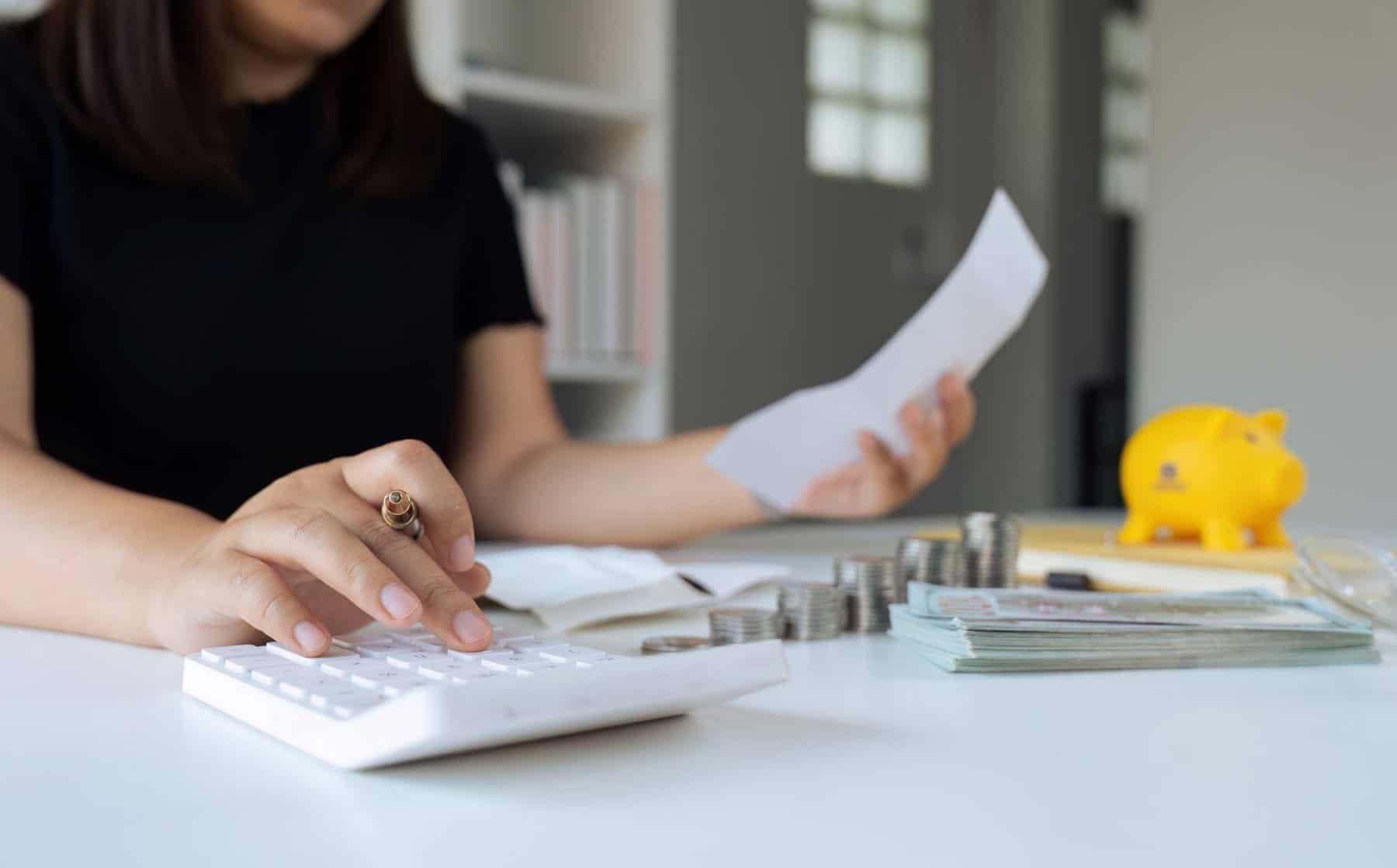 mulher com calculadora e papéis para analisar a poupança se consolidar créditos
