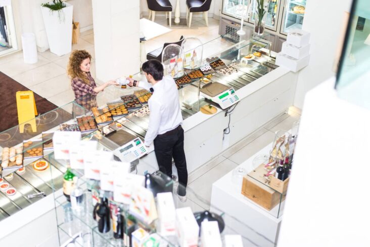 Loja onde se vendem produtos de café. Funcionária surge atrás do balcão a atender um cliente.