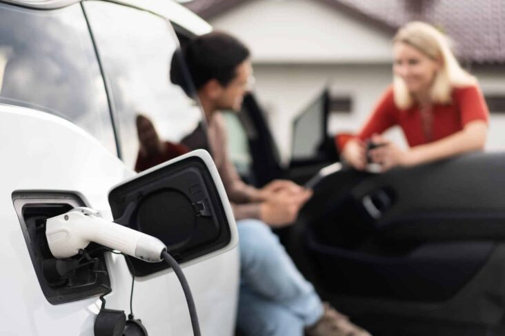 duas pessoas a falar sobre os apoios à compra de um carro elétrico, estando uma sentada num veículo elétrico