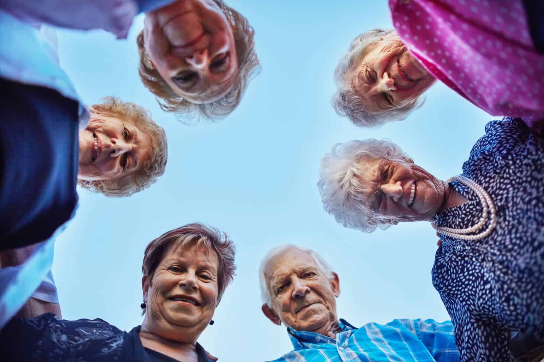 Seis idosos, cinco mulheres e um homem, estão em roda, a olhar para baixo.