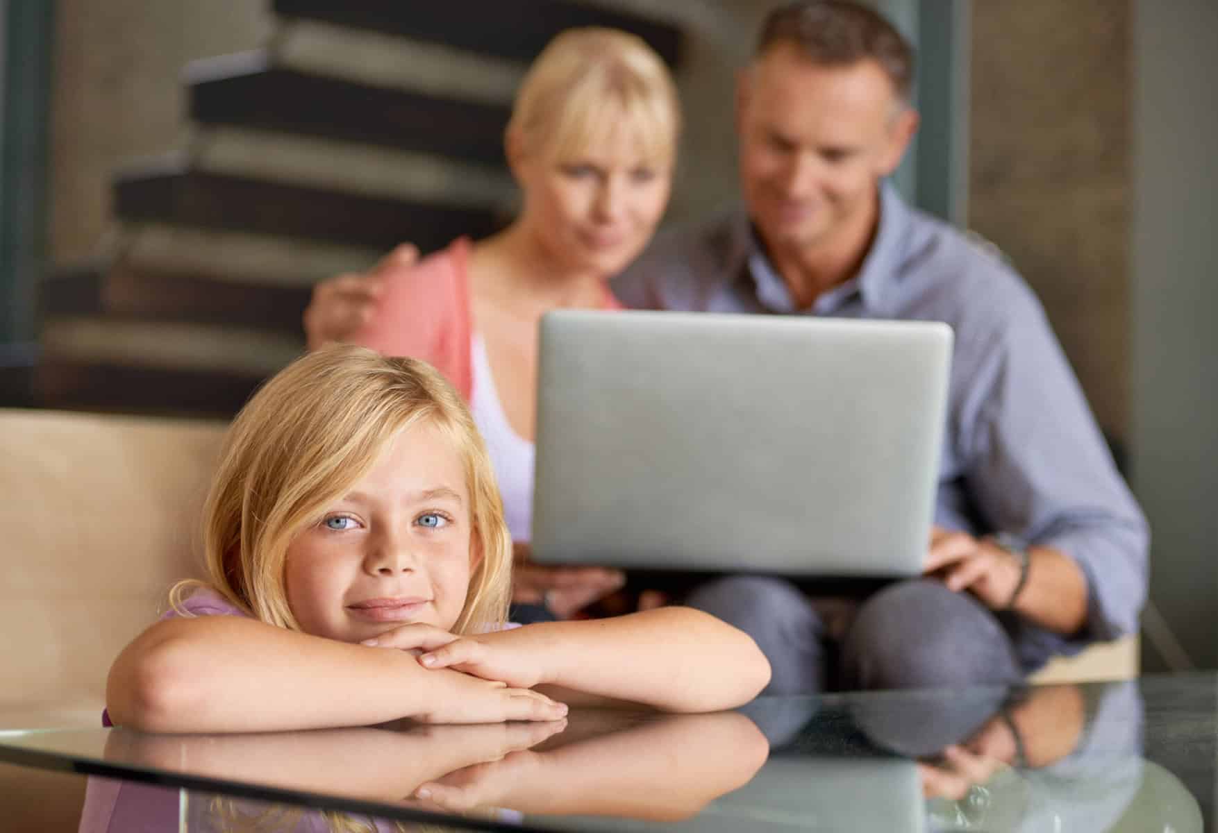 pais no computador a preencher a declaração de IRS com a filha sentada ao pé deles. Imagem a ilustrar os procedimentos para entregar a declaração de IRS para quem tem dependentes