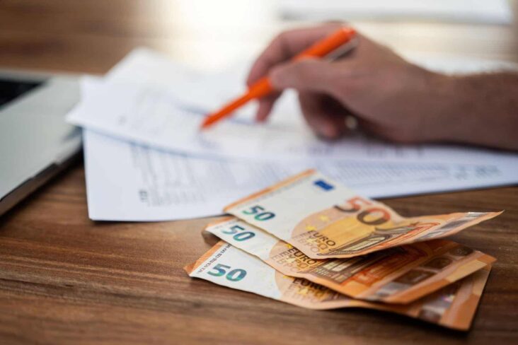 pessoal a preencher a declaração de rendimentos e notas de 50 euros em cima da mesa