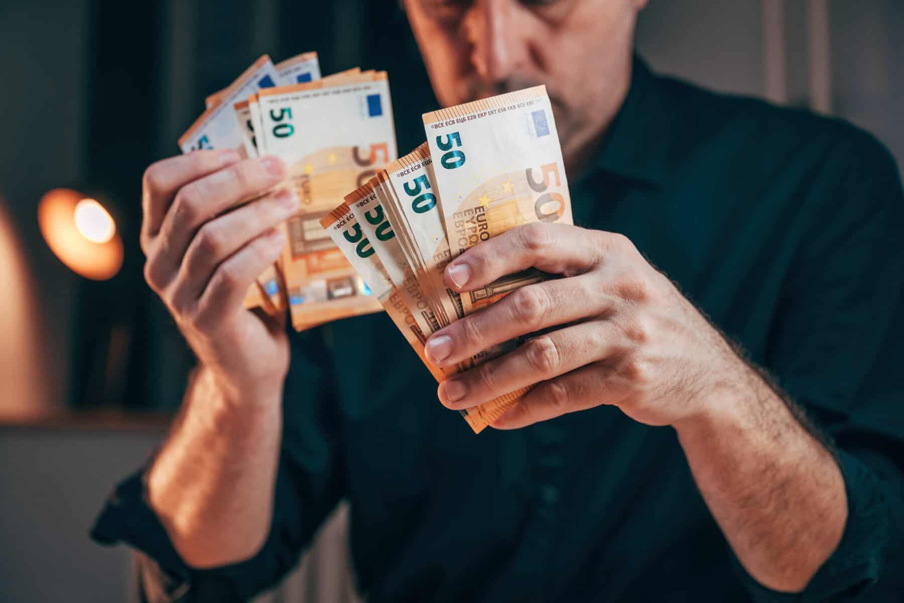 Homem com várias notas na mão após o reembolso de IRS a ilustrar Como usar o reembolso de IRS para reforçar as finanças pessoais