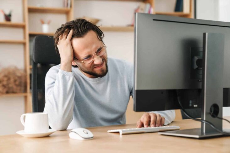 homem em frente ao computador com cara de preocupado após se atrasar a entregar o IRS