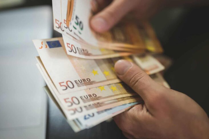 imagem de umas mãos a contar notas de 50 euros - para ilustrar artigo sobre prémio salarial e IRS