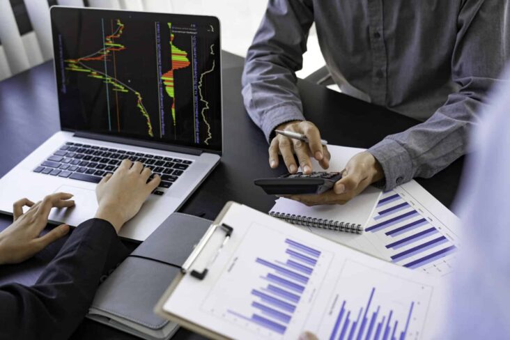Dois investidores analisam dados relacionados com ações, nomeadamente valores de dividendos
