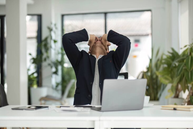 homem em frente ao computador com as mãos na cabeça após atrasar na entrega da declaração de IRS e ter uma perda de benefícios fiscais no IRS
